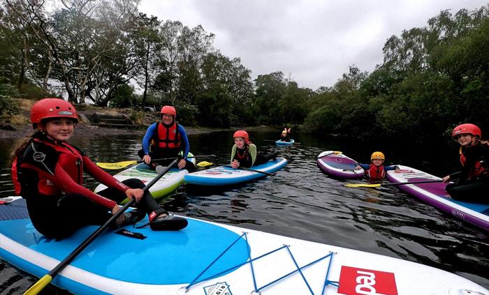 A group of paddleboarders sitting together on their boards.